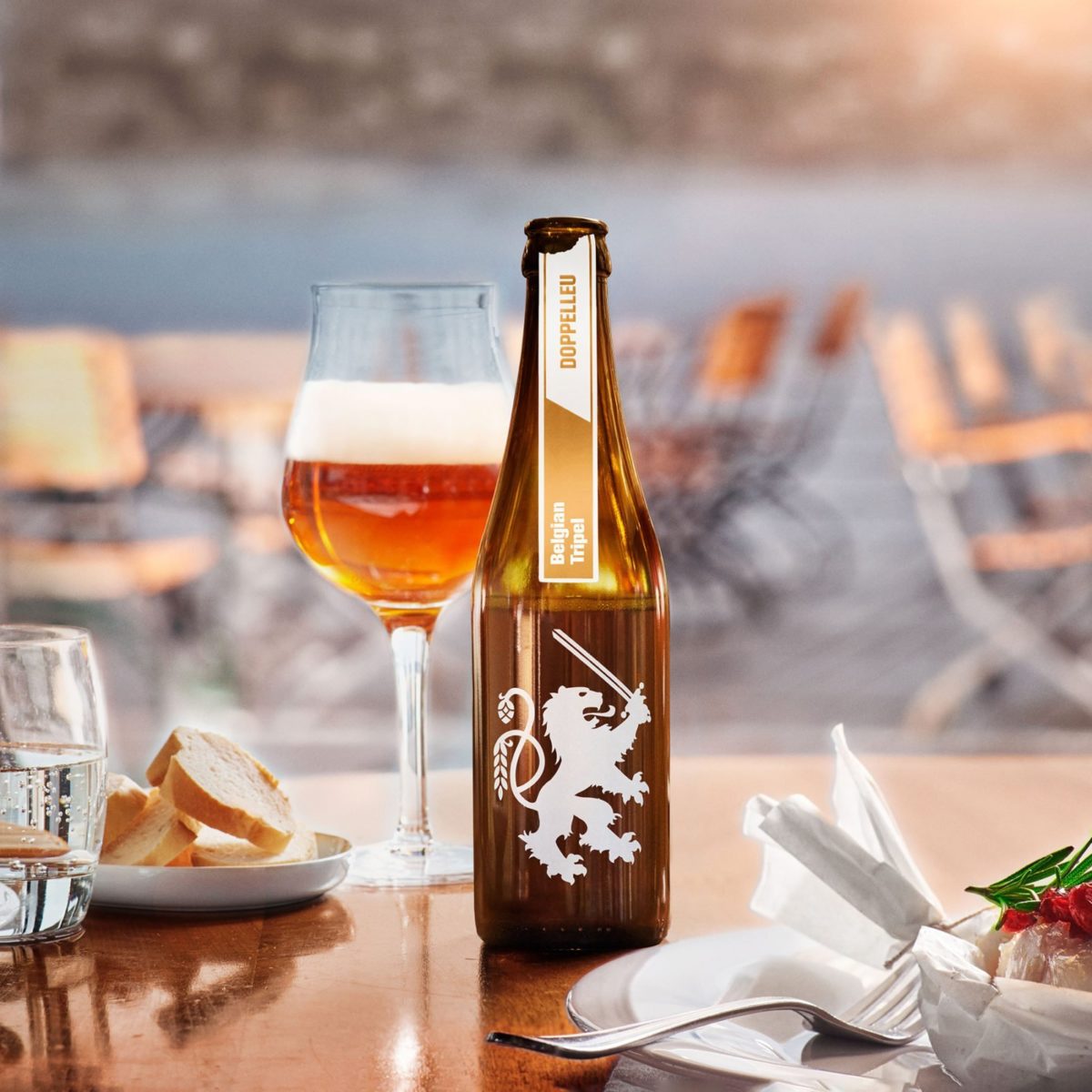 Doppelleu Belgian Tripel in der Flasche und eingeschenkt im Glas in einem Restaurant mit Häppchen, die ein ideales Food Pairing bilden